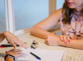 Pen and paper on table between two women